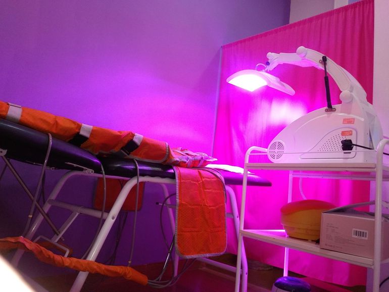Una habitación con una cama y una lámpara con luces moradas.