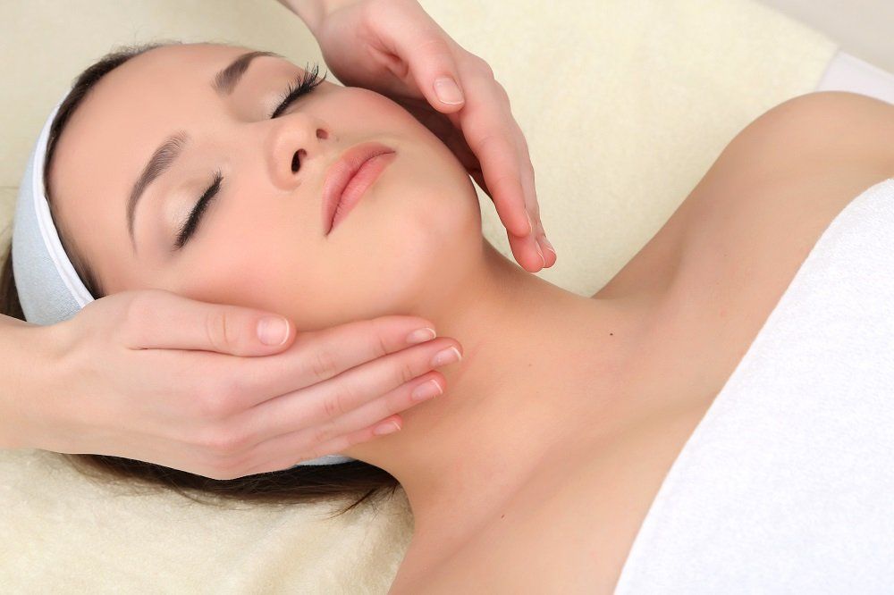 Una mujer está recibiendo un masaje facial en un spa.