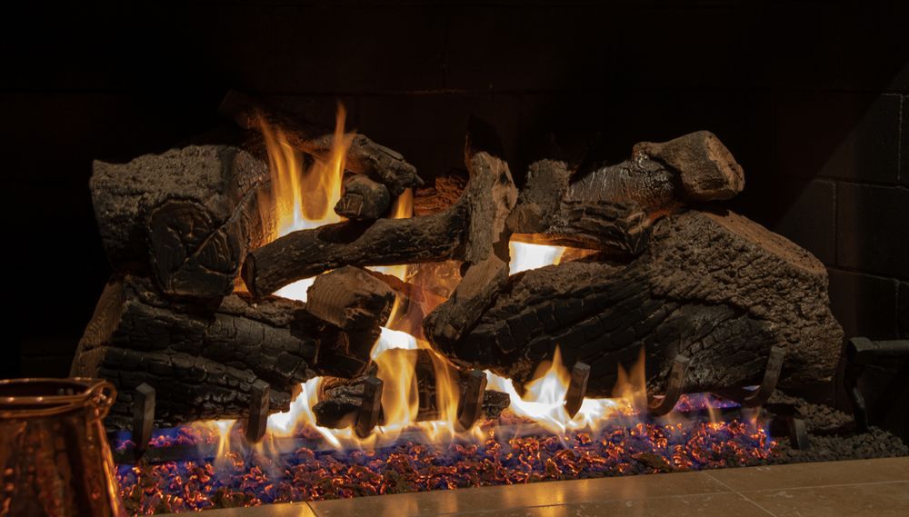 Decorative gas fireplace with glowing embers, orange flames, and stacked dark rocks