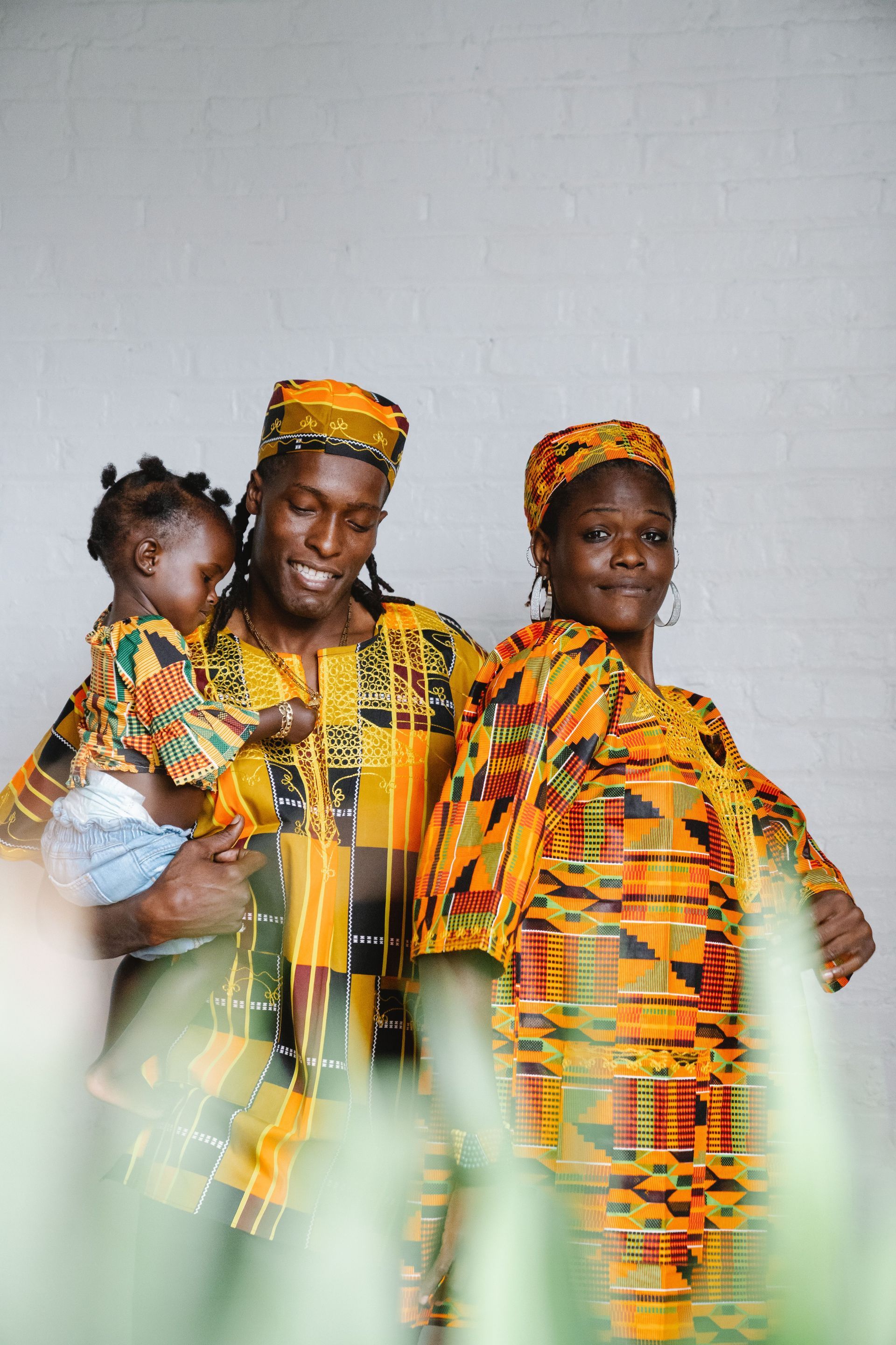 Three people in colorful matching outfits posing against a plain wall