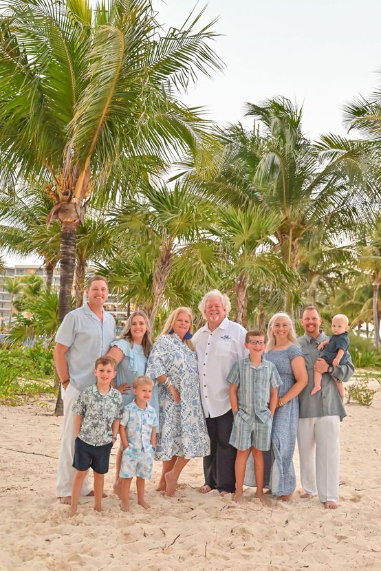 A large family is posing for a picture on a beach.