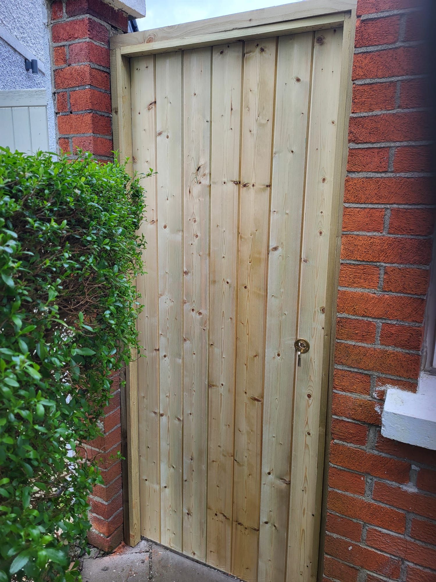 A wooden gate is sitting next to a brick wall.