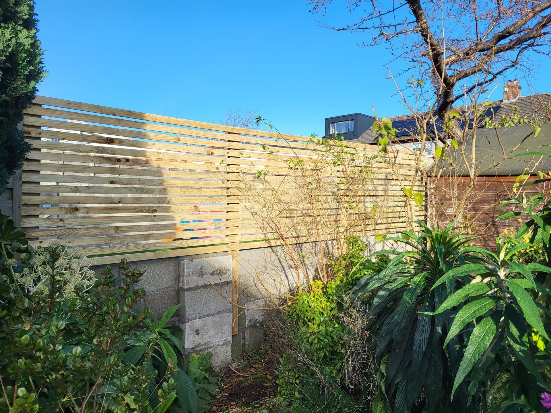 A wooden fence surrounds a lush green yard.