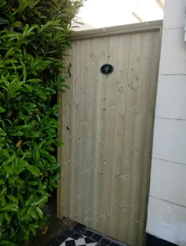 A wooden gate with the number 9 on it is surrounded by trees.