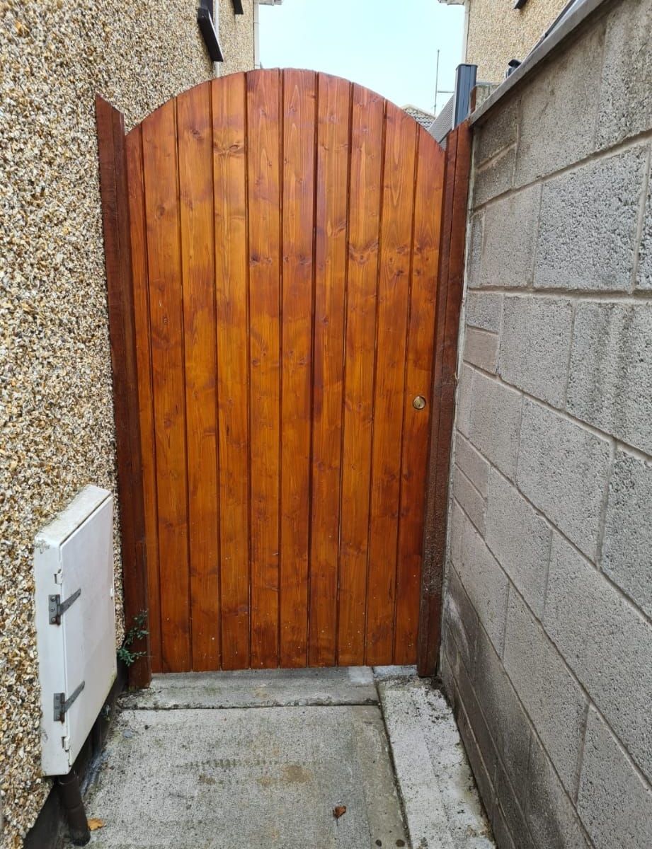 A wooden gate is between two brick walls