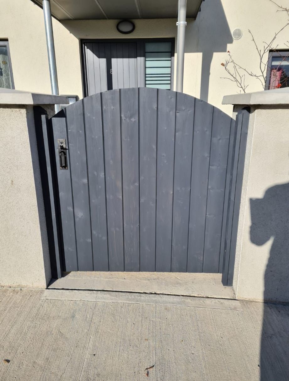 A gray wooden gate leading to a house