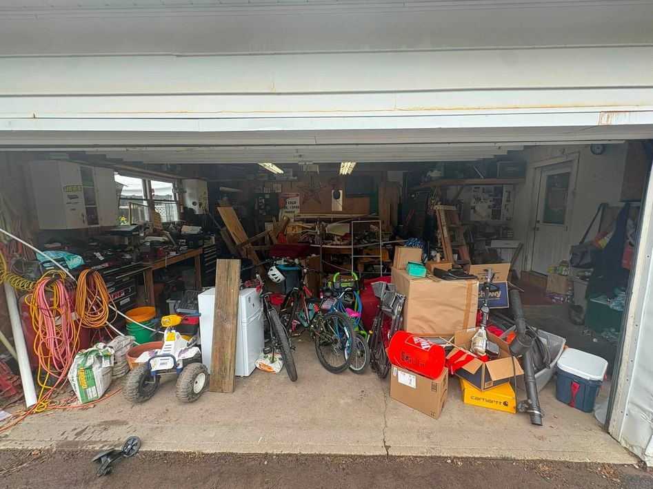 Open garage cluttered with bicycles, toys, boxes, and tools.