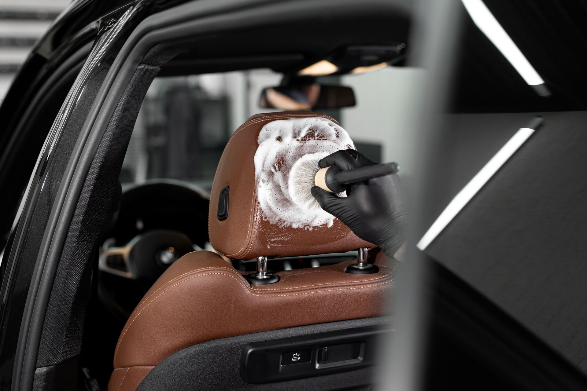 A person is cleaning the headrest of a car with a brush.
