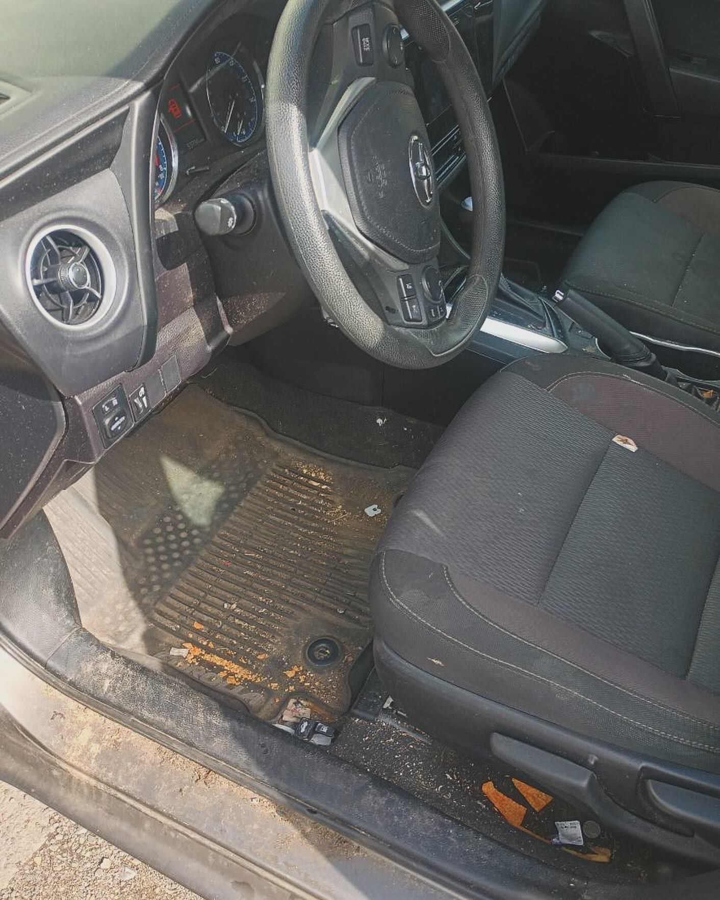 The inside of a dirty car with a steering wheel and seats.