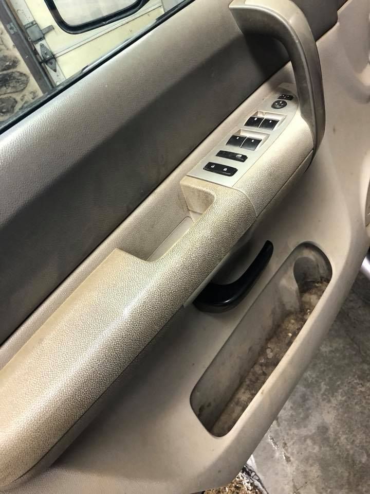 A close up of a car door with a dirty door handle.