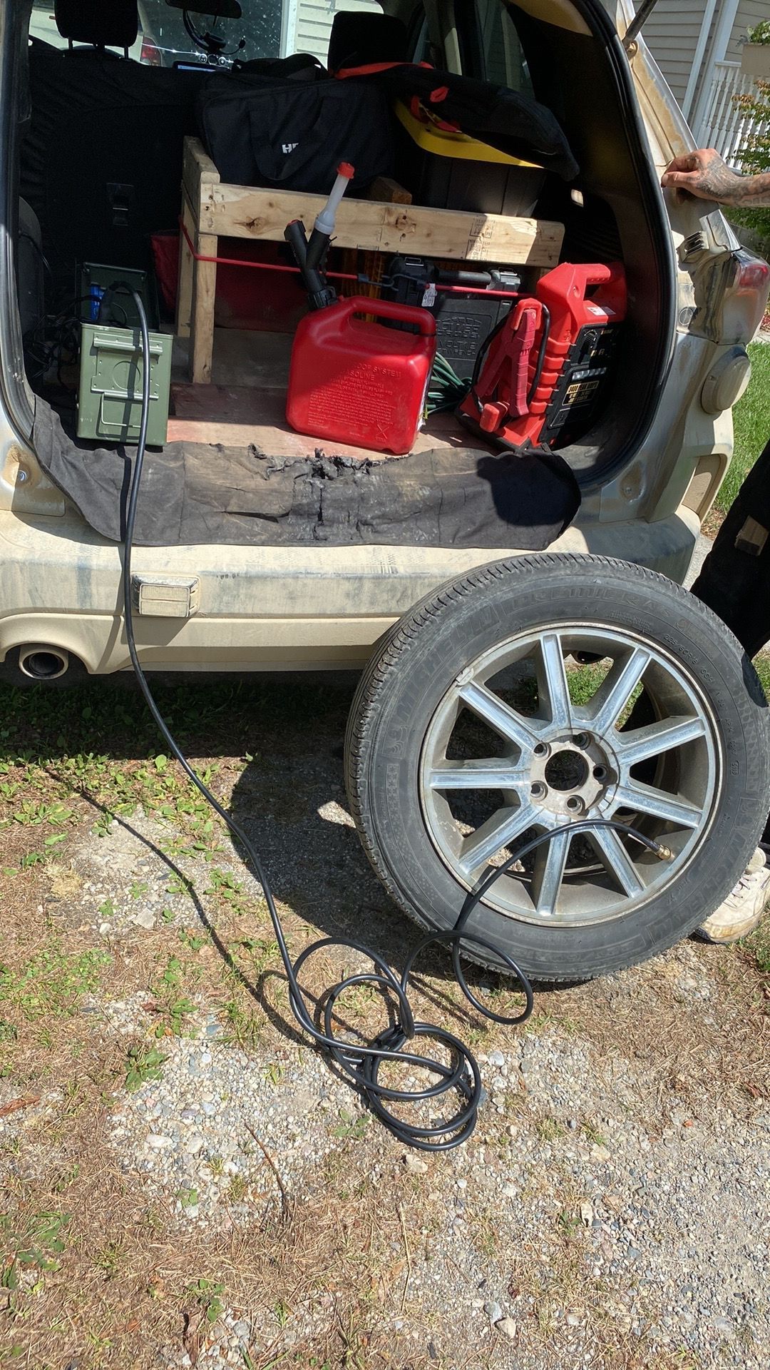 A person is plugging a tire into the back of a car.