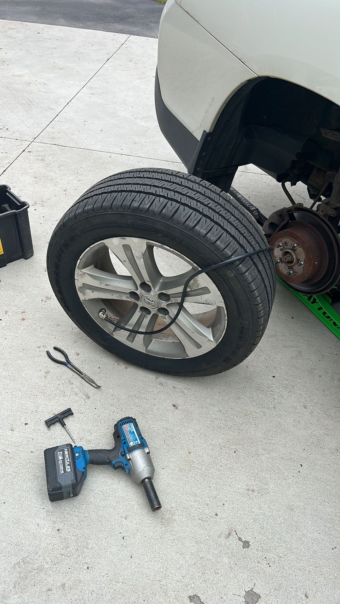 A tire is being changed on a car with a wrench.