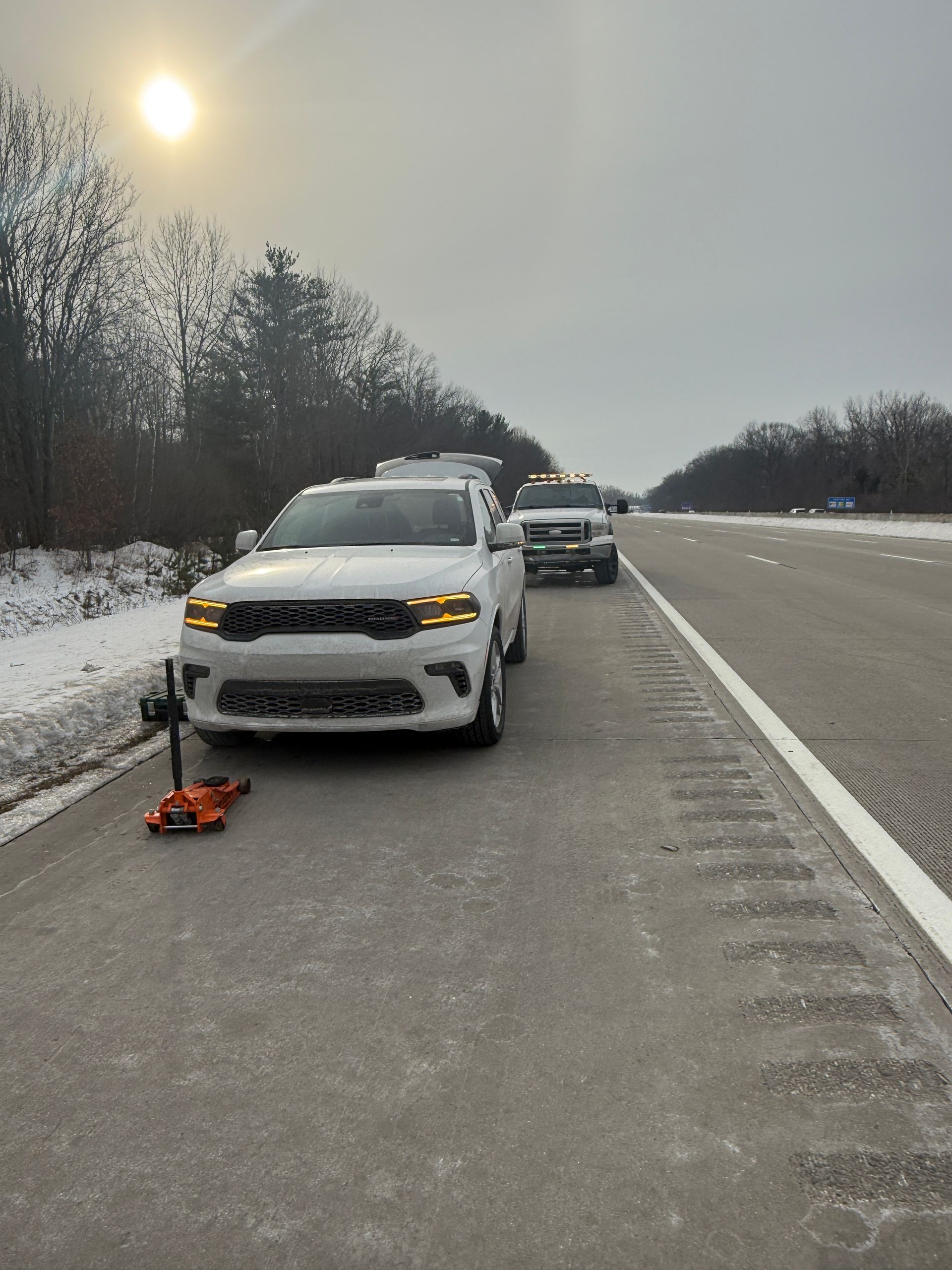 A white car is parked on the side of a highway.