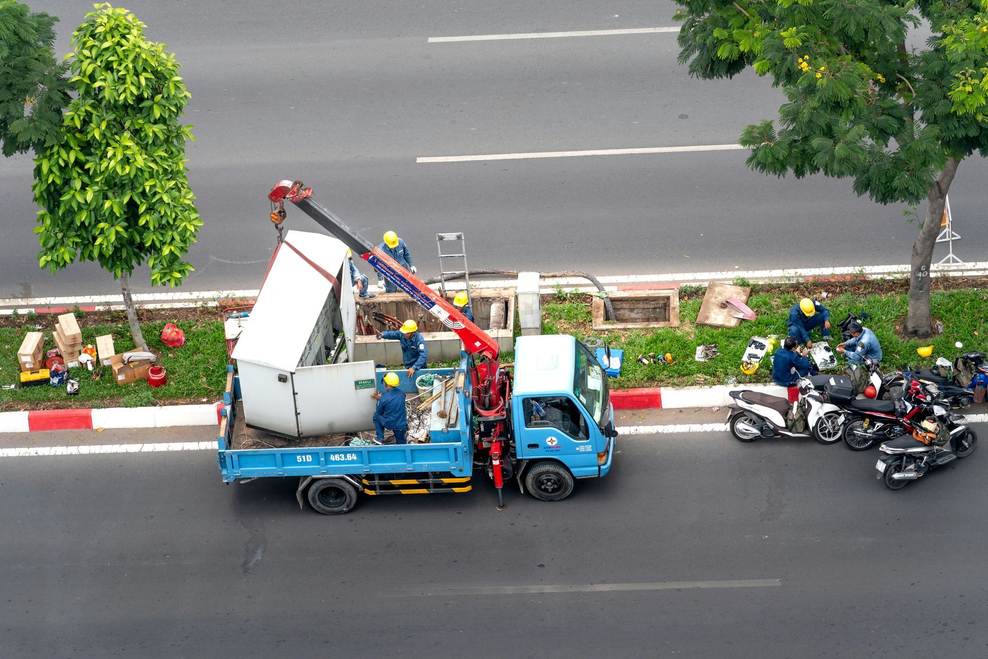A blue truck with a crane on the back is parked on the side of the road