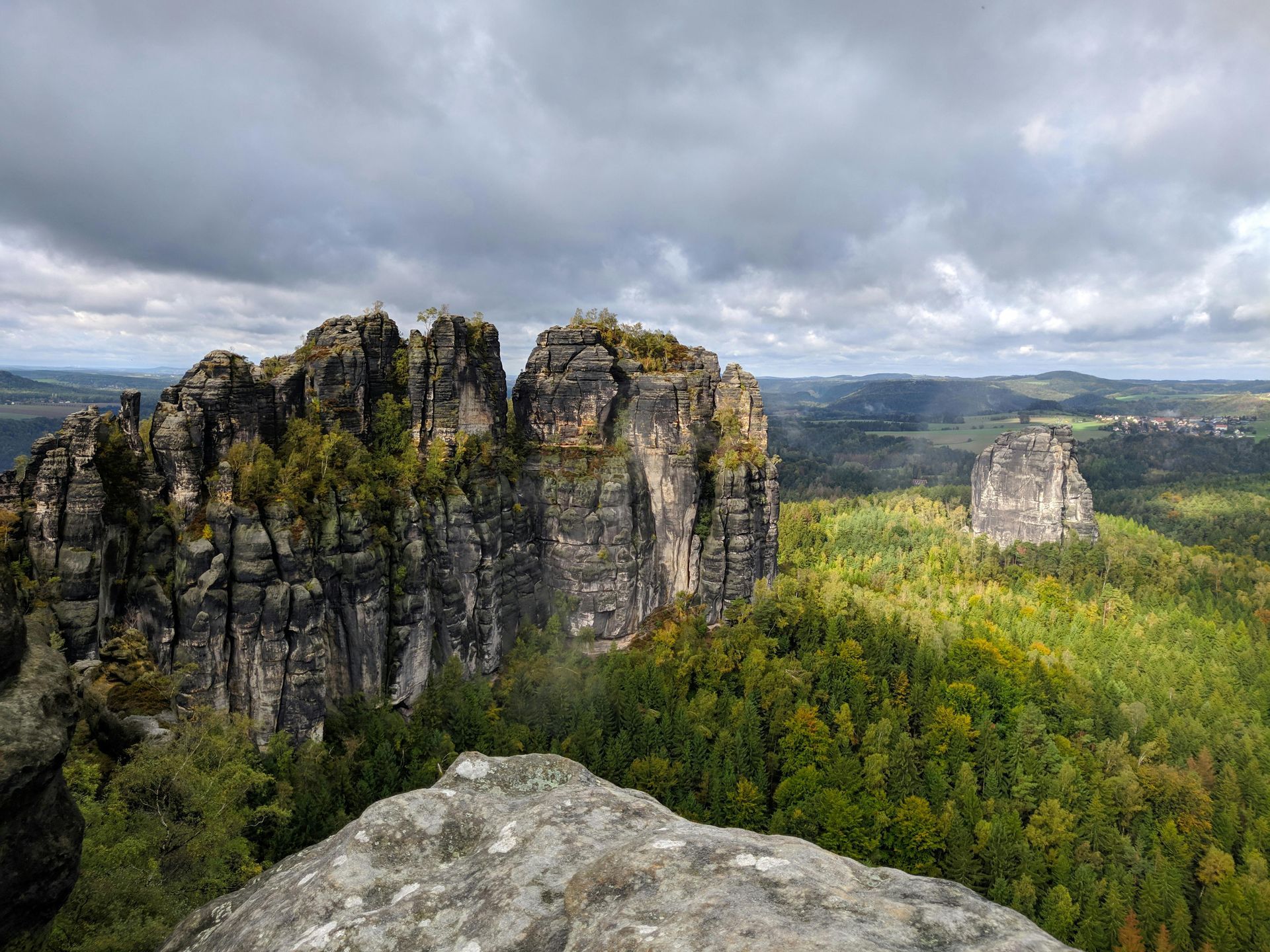 A view of a valley with mountains and trees from a cliff.
