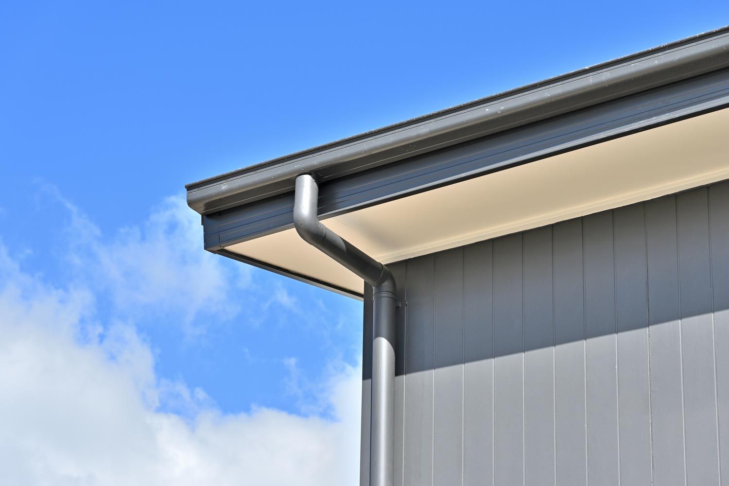 A gutter on the side of a building with a blue sky in the background.