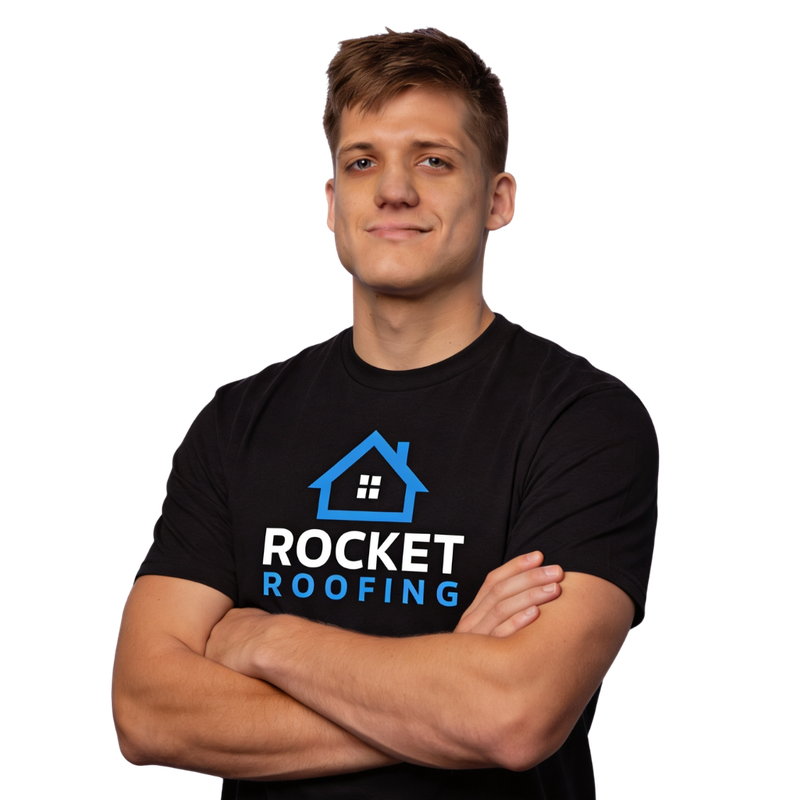 Person in a black Rocket Roofing T-shirt, standing with arms crossed and smiling on a white background