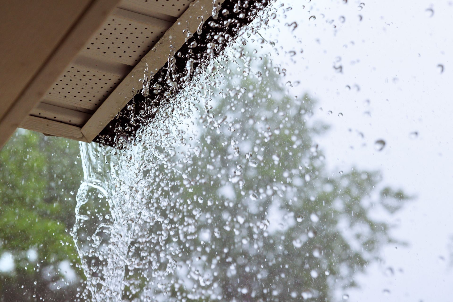 Rainwater splashing from a roof gutter during a storm