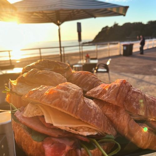 A Table Topped With Plates Of Food Including Pancakes Eggs Bacon And Toast — Beach Bums Cafe In Forster, NSW