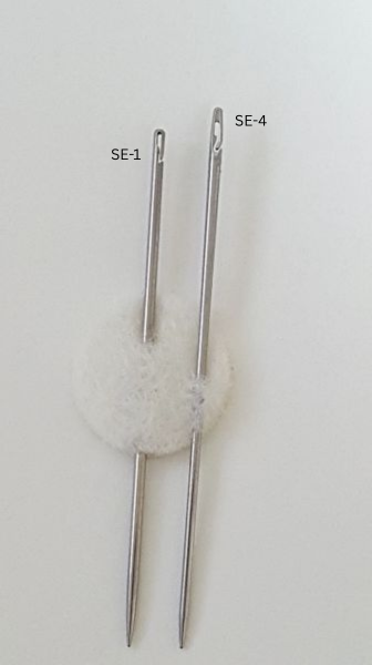 Close-up of a metal tool tip with a narrow slot and rounded opening against a beige background