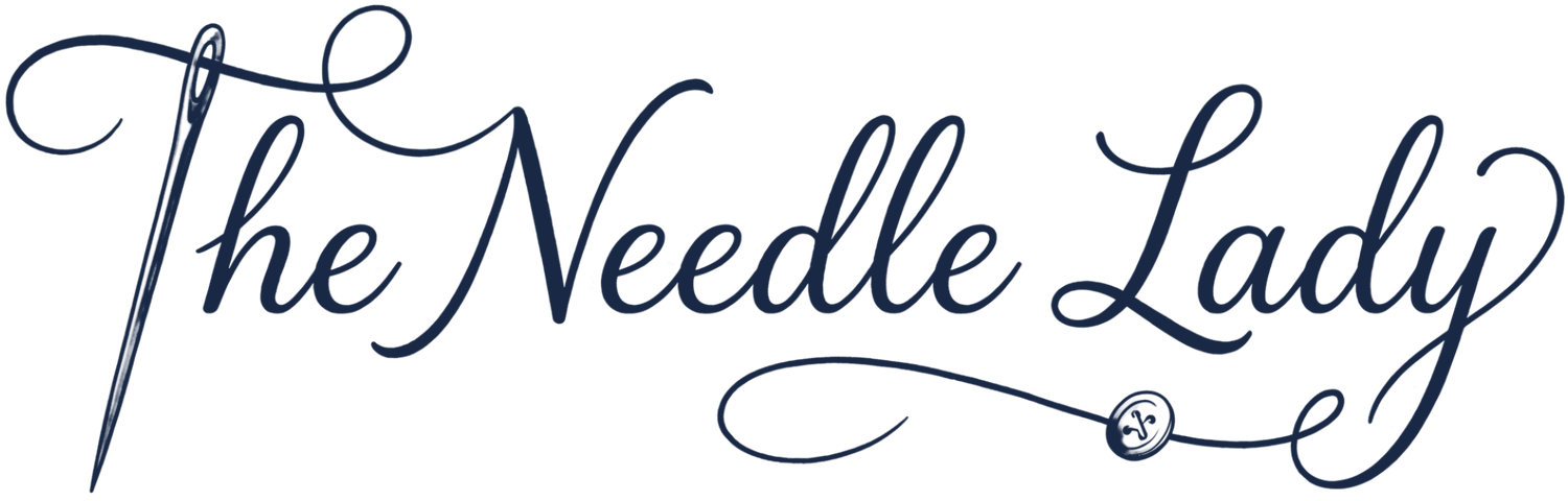 “The Needle Lady” in elegant blue script with a needle and thread decorative flourish