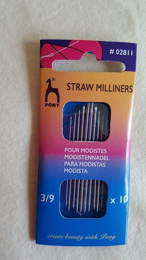 Packaging for straw milliners, orange and pink box with four blue striped hair rollers visible inside
