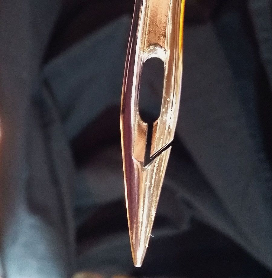 Close-up of a sewing machine needle piercing fabric against a warm background