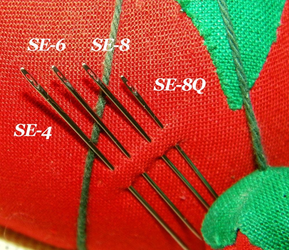 Needles and colorful spools of thread on a sewing surface