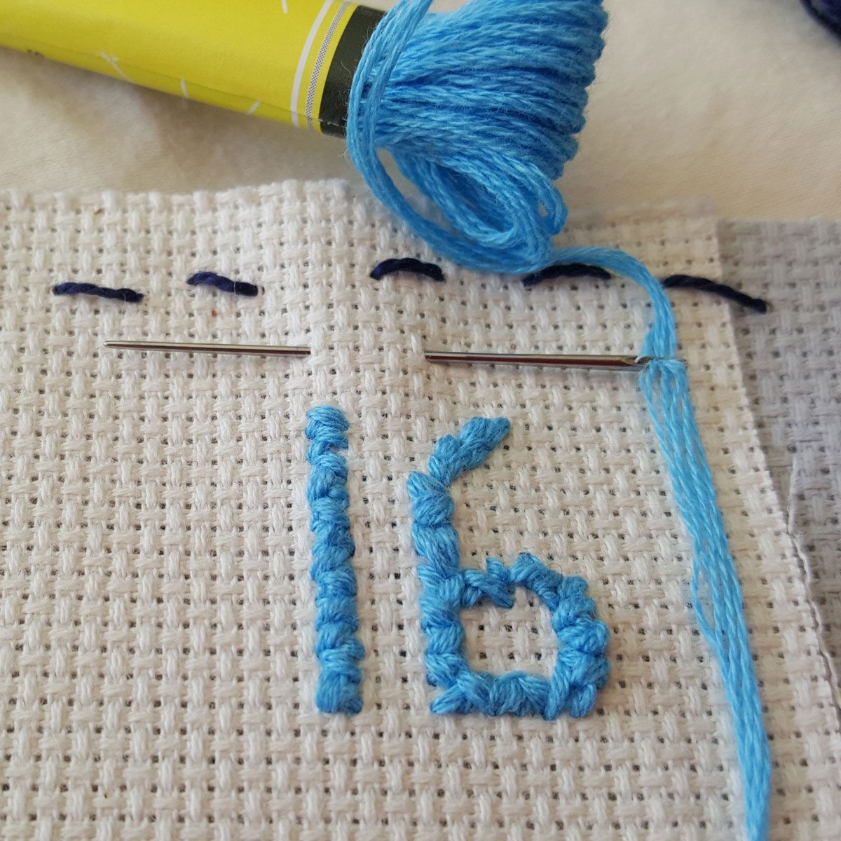 Dark blue ball of yarn with a knitting needle threaded through it.