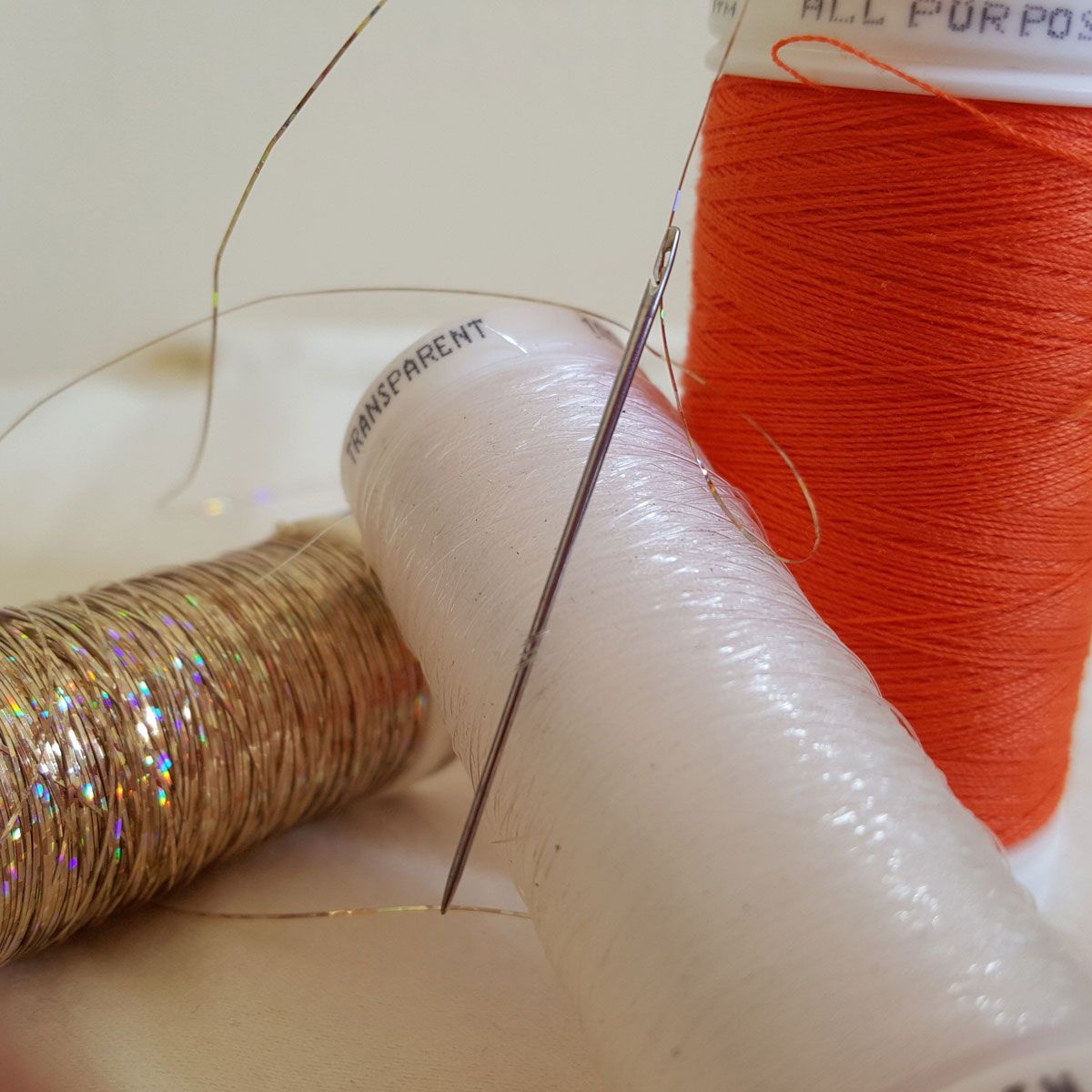 Needles and colorful spools of thread on a sewing surface