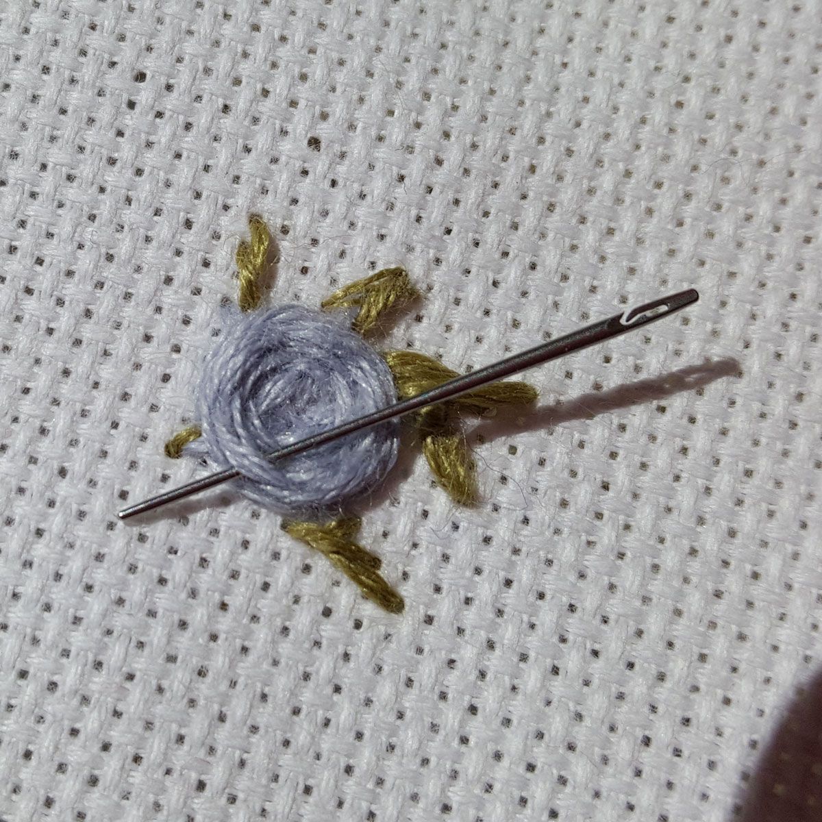 Small blue snail on white fabric, with two long dark antennae and yellow-green feet.