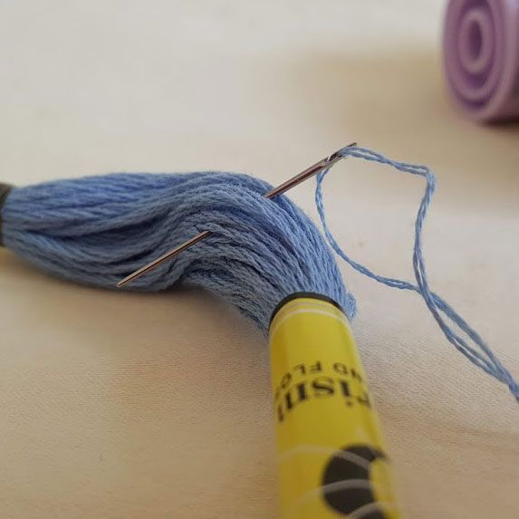 Small blue snail on white fabric, with two long dark antennae and yellow-green feet.