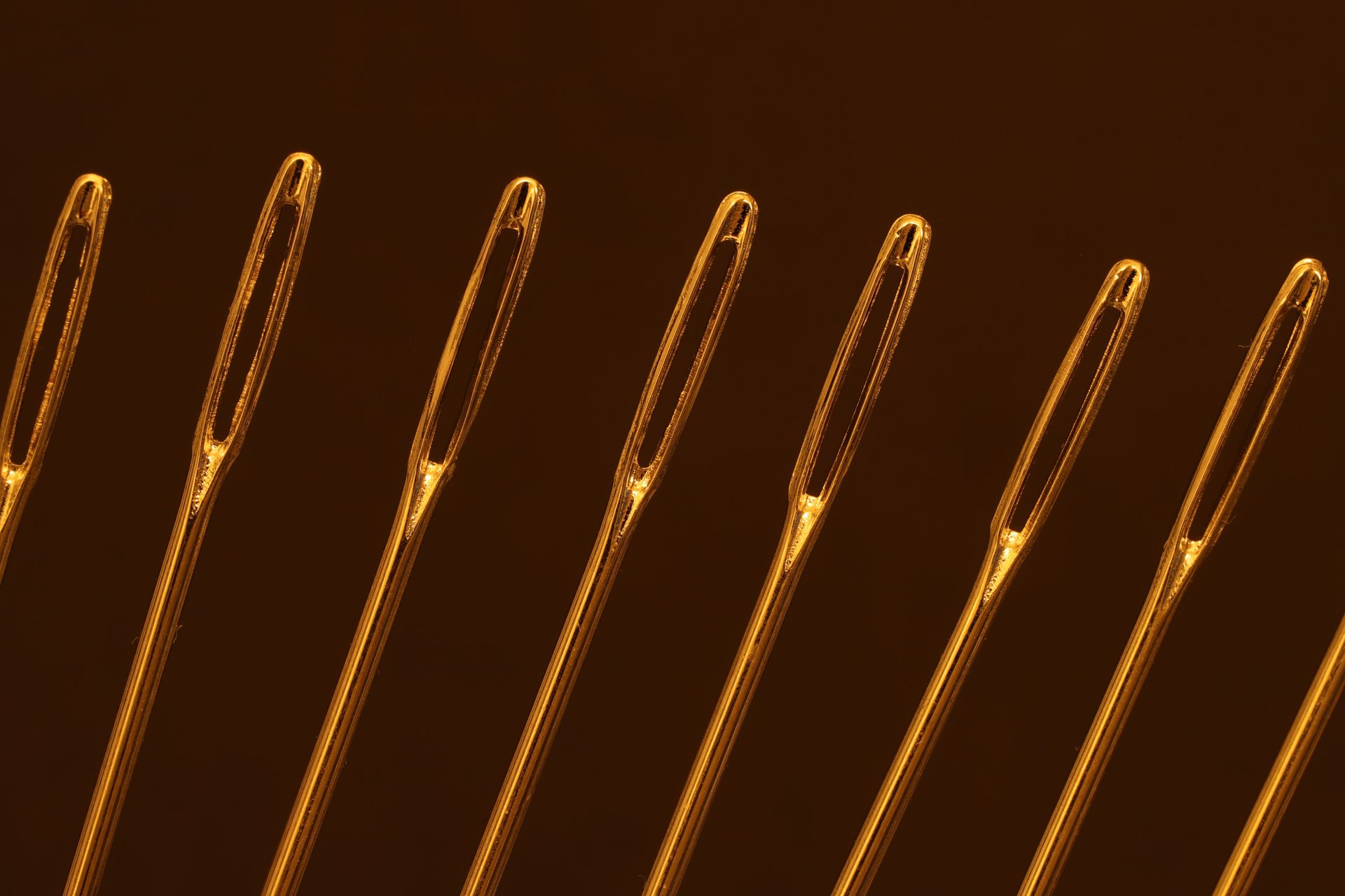 Orange-gold metallic wires or pins arranged diagonally on a dark brown background