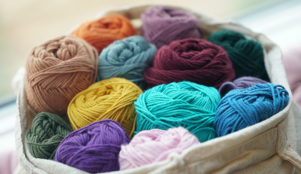 Basket filled with colorful yarn skeins in assorted bright and pastel shades