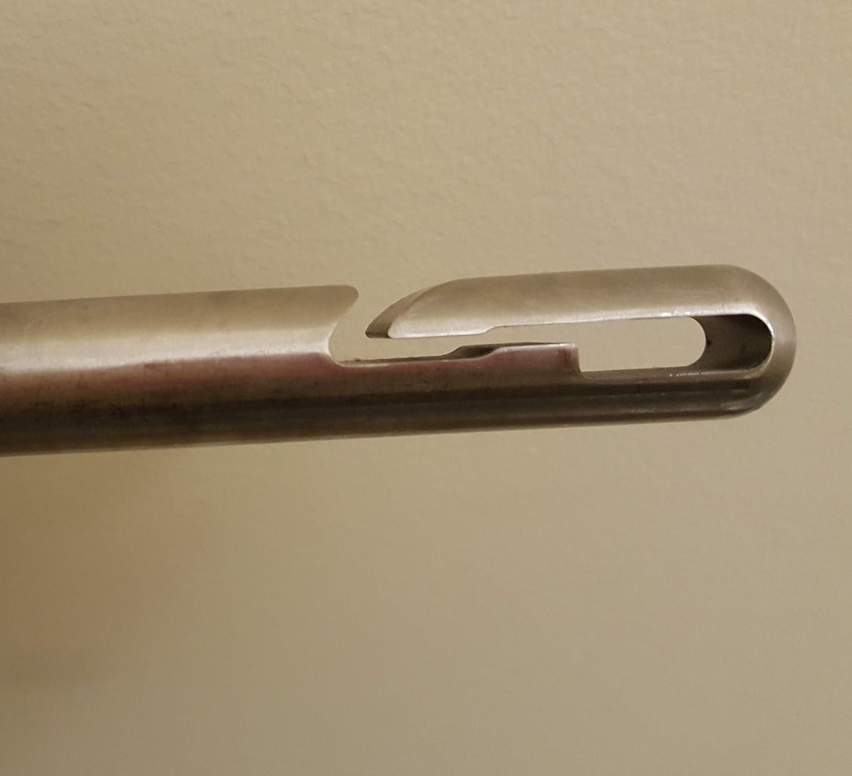 Close-up of the first edition Spiral Eye needle with a slot and rounded opening on a beige background