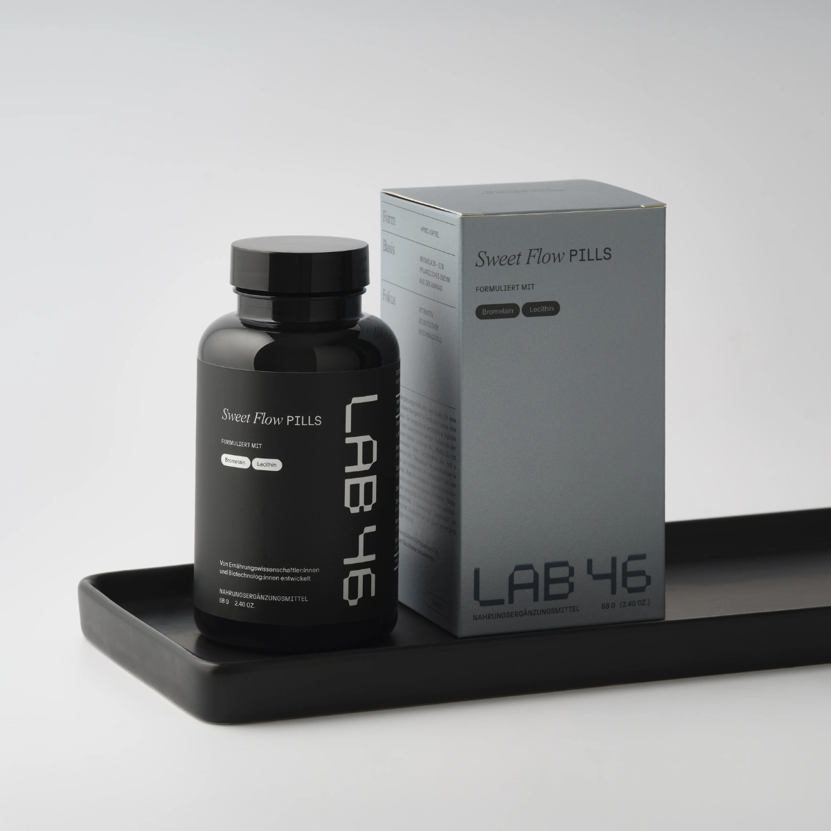 Schwarze LAB 46-Flasche neben grauer Schachtel auf einem schwarzen Tablett vor hellem Hintergrund