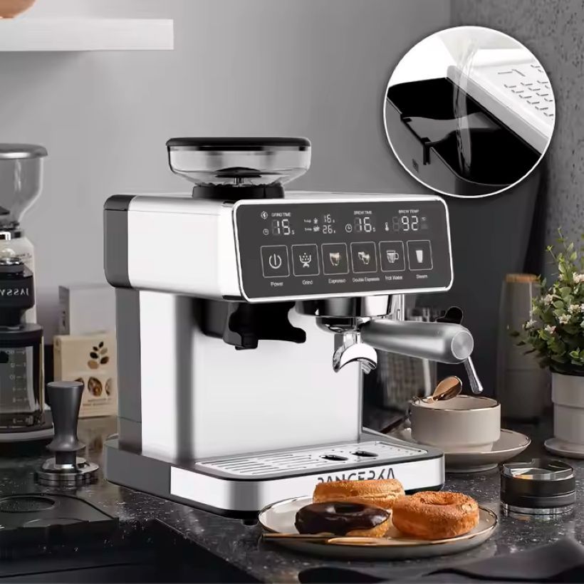 Máquina de café expreso plateada y negra sobre una encimera, con donas y una taza de café.