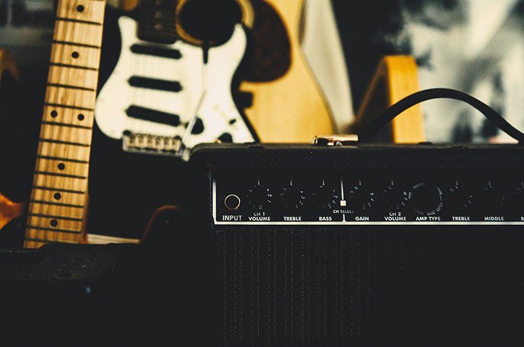 An electric guitar is sitting next to an amplifier.