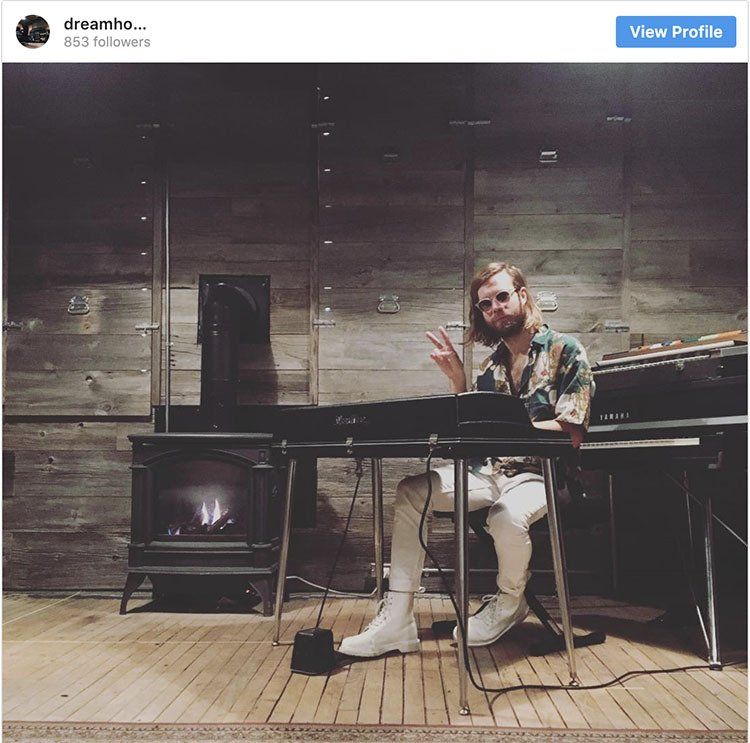 A man is sitting at a piano giving a peace sign