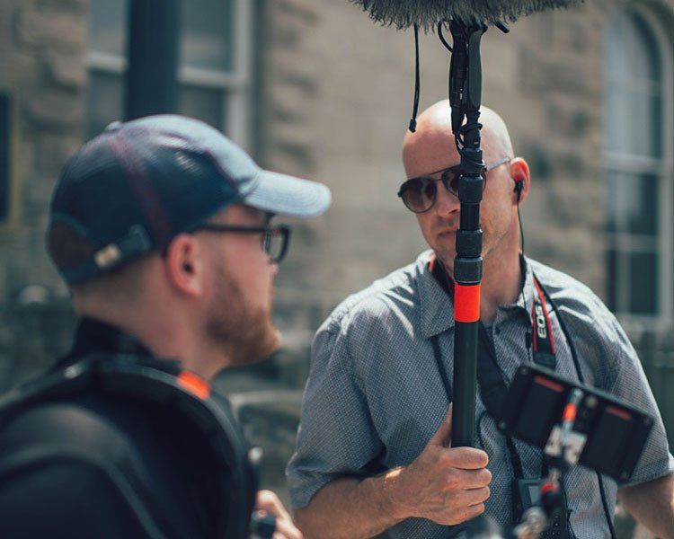 Two men are standing next to each other in front of a microphone.