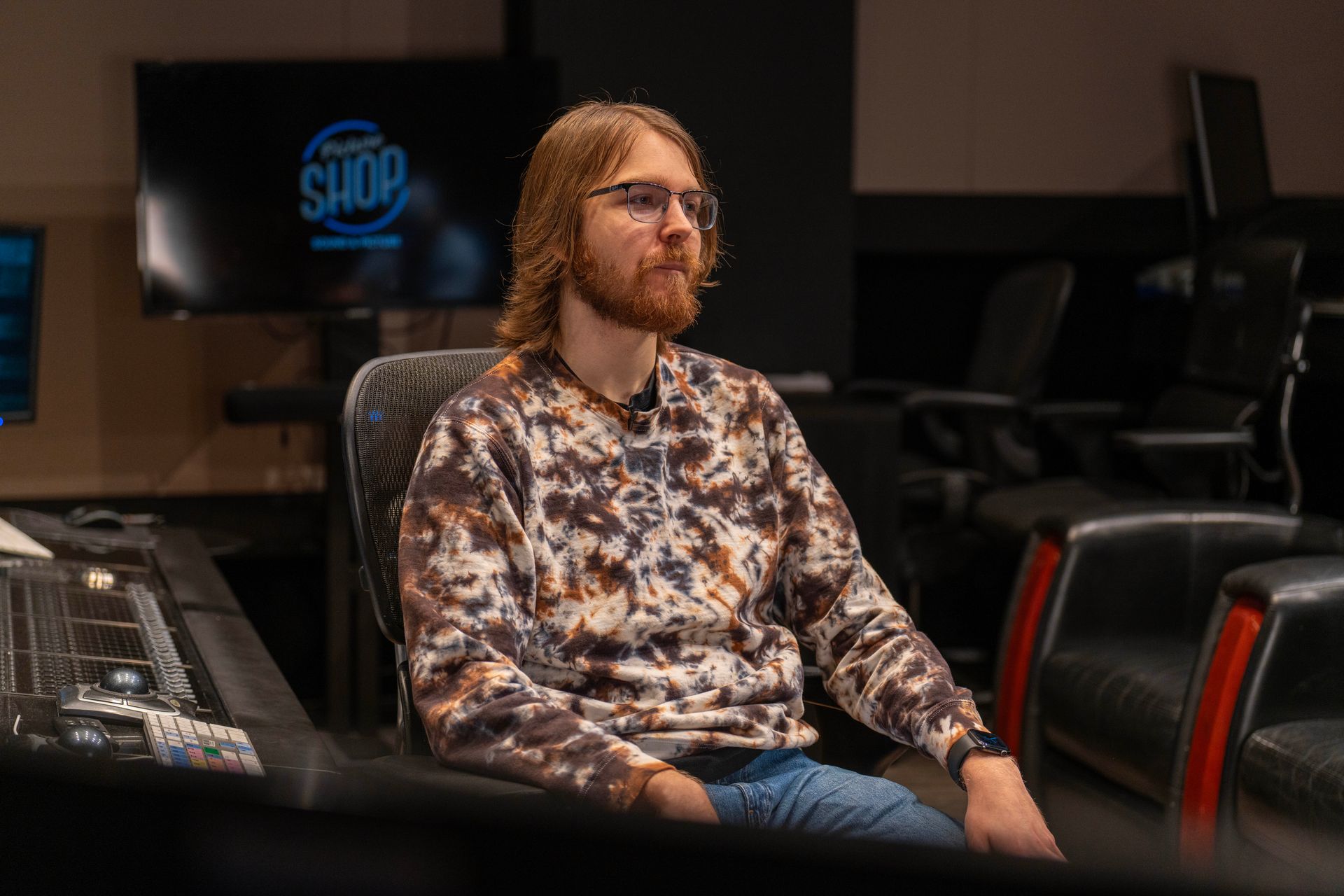 Gabriel P seated in a dark theater room, wearing a patterned sweater and jeans, looking to the side.