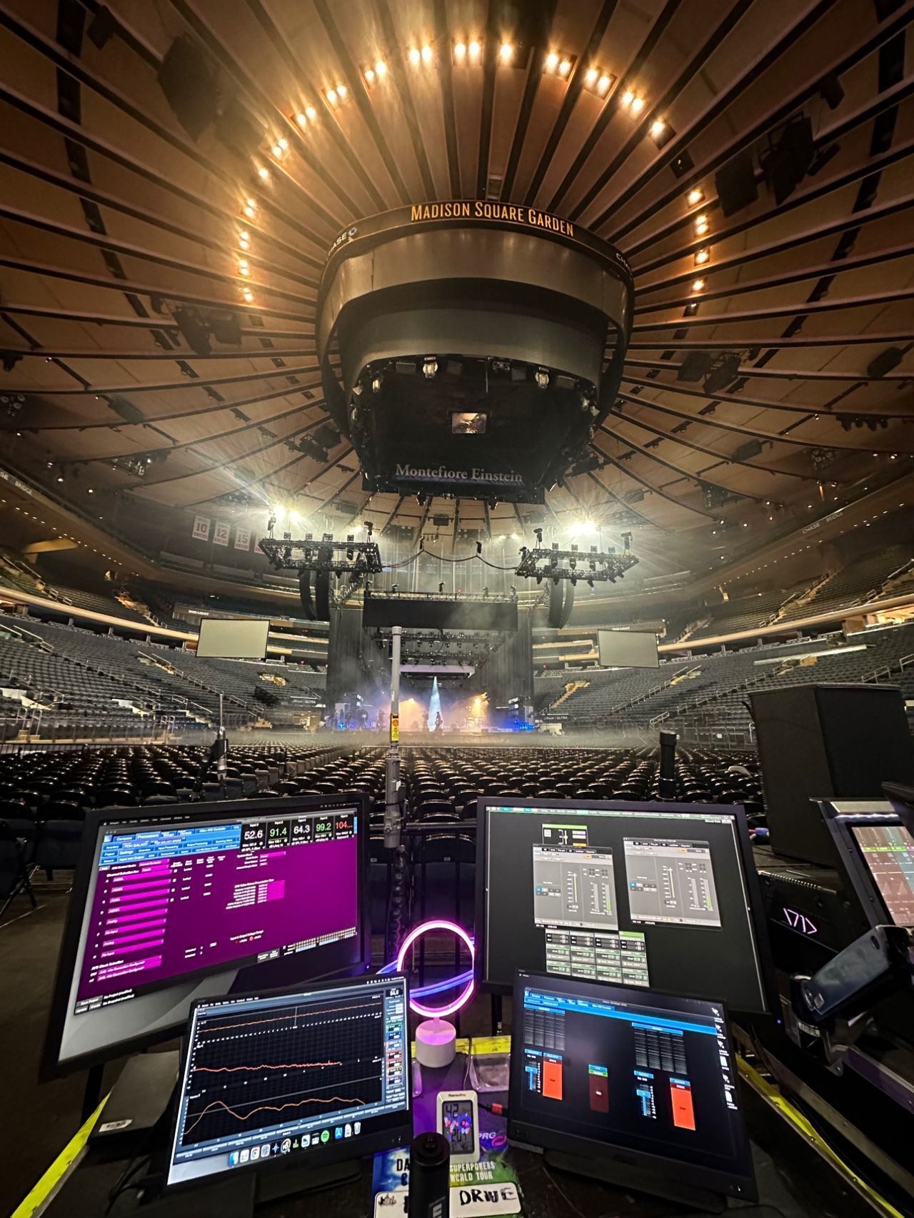 A computer monitor is sitting in front of a stage in a stadium.