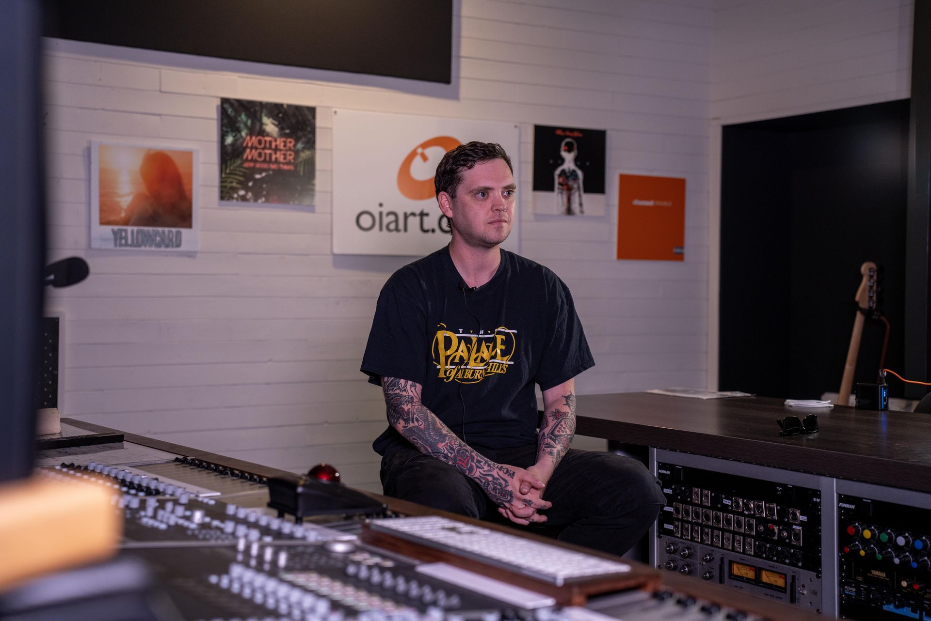 Matt sitting in a recording studio, surrounded by audio equipment and wall posters.