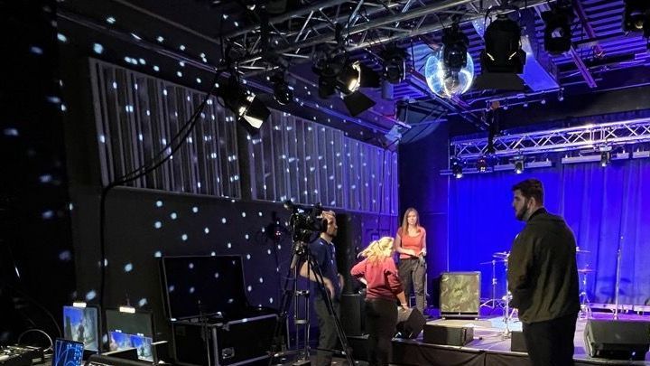 A group of people are standing on a stage in a dark room.