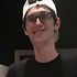 A young man wearing glasses and a hat is smiling for the camera.