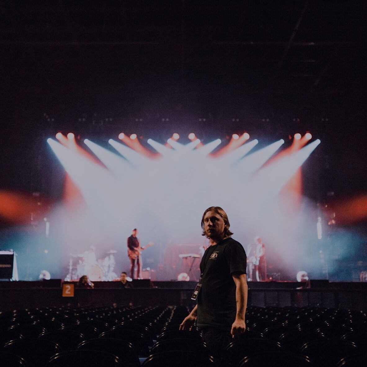 Nathan Bond in black shirt in front of stage at concert.