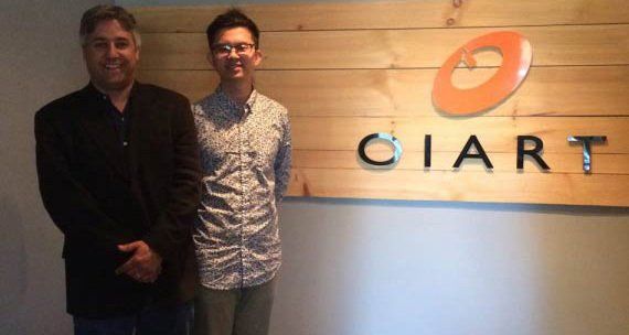 Adam Tsui and another person standing in front of a wooden sign with