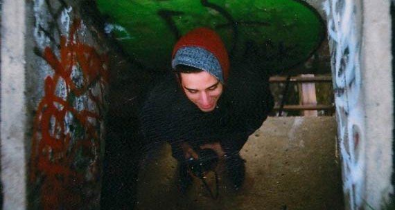 Arthur Bastos is kneeling down in a tunnel with graffiti on the walls.