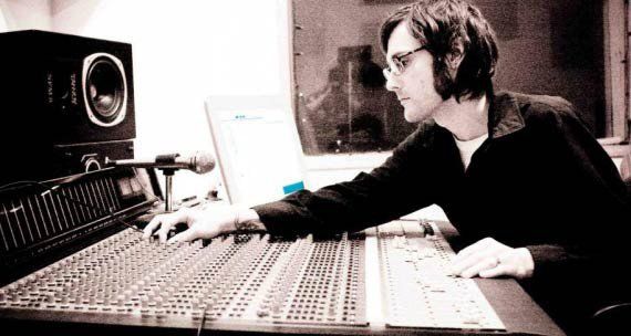 Chris Colvin is sitting at a desk in front of a computer.