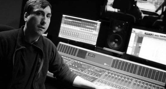 Damian Kearns is standing in front of a computer in a recording studio.
